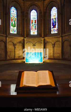 Genf, Schweiz - 19. Juli 2019: Religiöse Buch auf vertikale Bild in Evangelisch-reformierten Kathedrale St. Pierre erfasst. Glasmalerei mit religiösen Motiven im Hintergrund. Christentum, glauben. Stockfoto