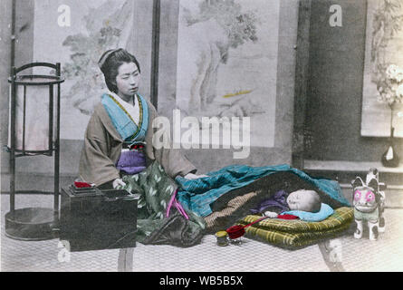 [1890s Japan - Japanische Mutter und Kind] - eine Mutter im Kimono und traditionelle Frisur wacht über Ihr Kind schlafen auf einem Futon. Zwei Spielzeuge sind in der Nähe von seinem Kopf. Ein Nähset mit einem Stift Kissen steht auf dem Boden. Daneben steht eine Lampe Andon. 19 Vintage albumen Foto. Stockfoto
