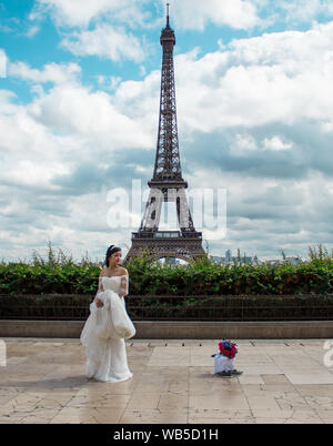 Paris/Frankreich - 10. September 2017: Asiatische Braut warten auf Ihren Papierkorb das Kleid Sitzung mit dem Eiffelturm im Hintergrund fotografiert zu werden. Stockfoto