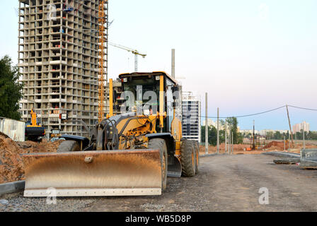 Сonstruction Maschine Motorgrader auf einer Baustelle auf dem Boden und Kies und Steine für den Bau einer neuen Asphalt. Straße konstruieren Stockfoto