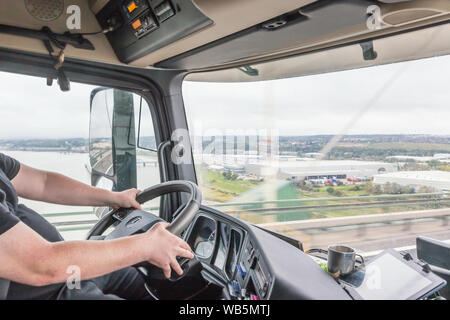 Der LKW-Fahrer im Inneren der LKW-Kabine. Der Stapler kreuzt die Queen Elizabeth II Brücke über die Themse in der Nähe von London. Stockfoto