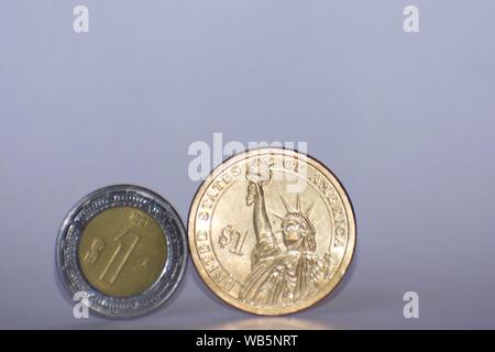 American Gold Dollar neben peso Münze aus Mexiko vor einem weißen Hintergrund Stockfoto