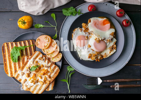 Spiegeleier mit Pilzen und Toast mit Frischkäse. Leckeres Frühstück. Ansicht von oben Stockfoto