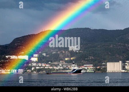 Ein Regenbogen glänzend über PSV Platform Supply Vessel Norden Pomor, Warten auf Liegeplatz außerhalb der Hafen von Bergen, Norwegen. Stockfoto