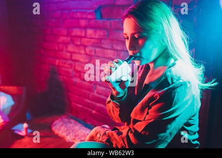 Frau raucht eine e-Zigarette liegen auf dem Bett im Zimmer. Raucher Konzept dampfen Stockfoto