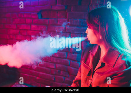 Frau raucht eine e-Zigarette liegen auf dem Bett im Zimmer. Raucher Konzept dampfen Stockfoto