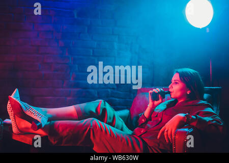 Frau raucht eine e-Zigarette liegen auf dem Bett im Zimmer. Raucher Konzept dampfen Stockfoto
