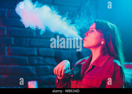 Frau raucht eine e-Zigarette liegen auf dem Bett im Zimmer. Raucher Konzept dampfen Stockfoto