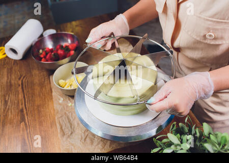 Konditor Schneiden der Biskuit auf lagen. Kuchen Produktionsprozess Stockfoto