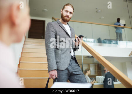 Portrait von gutaussehenden jungen Mann mit Anzug unten kommen, Treppen, Smartphone, kopieren Raum Stockfoto