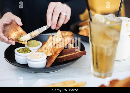 Selektive Nahaufnahme einer Person, die Sauce auf Nachos verteilt Stockfoto