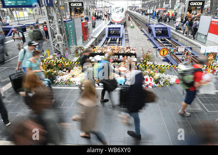 20. August 2019, Hessen, Frankfurt/Main: Passanten vorbei an einem Denkmal am Gleis 7 des Hauptbahnhofs, wo Blumen, Kuscheltiere und Ausdrucksformen der Trauer versammelt haben (Foto mit langer Verschlusszeit). Am 29. Juli 2019, ein achtjähriger Junge und seine Mutter wurden in das Bett geschoben. Die Frau selbst konnte einfach auf die Seite speichern, ihr Sohn war von einem ICE erfasst und starb. (Dpa' Existenz und Zuhören: Psychologen und Helfer der Eisenbahn in Aktion') Foto: Arne Dedert/dpa Stockfoto