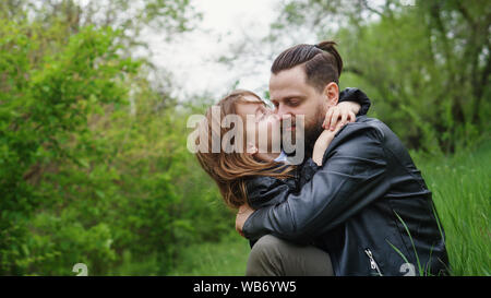 Modernes, stilvolles Familie Fuß in den Park. Tochter Küsse und Umarmungen Vati. Zeit zusammen. Familie suchen. Urban casual Outfit. Stockfoto