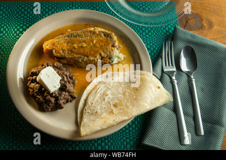 Ein Ausgestopfter mexikanischen Chile mit mexikanischen Bohnen und Reis auf einen Teller. Stockfoto