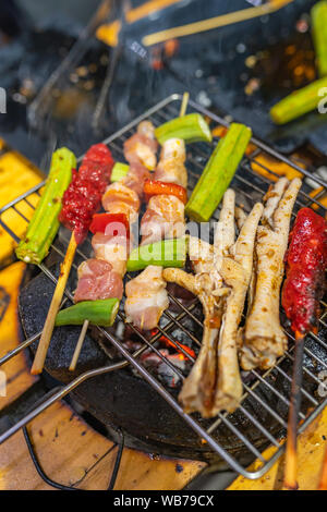 Grillen, Schwein am Spieß, Huhn und Gemüse auf Holzkohle Herd Stockfoto
