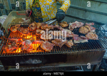 Frau grillen Schweinekotelett und Rippen auf brennende Holzkohle Herd Stockfoto