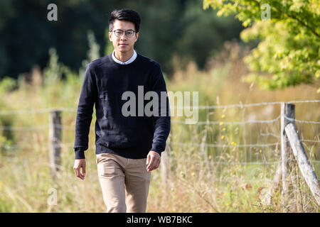 20. August 2019, Niedersachsen, Göttingen: Ray Wong, ein ehemaliger Aktivist in Hongkong und als politischer Flüchtling in Deutschland seit 2018, Spaziergänge über eine Wiese. (Dpa: "Hongkong Aktivist Wong fordert mehr Unterstützung aus dem Westen") Foto: Swen Pförtner/dpa Stockfoto