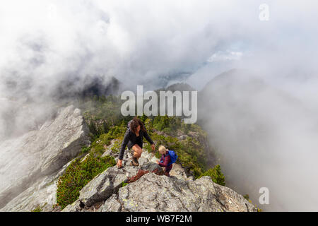 Abenteuerliche Mädchen ist Wandern auf einem steilen Weg nach oben einen schönen Rocky Mountain bei einem bewölkten Sommermorgen. Auf Crown Mountain, North Vancouver, BC genommen Stockfoto