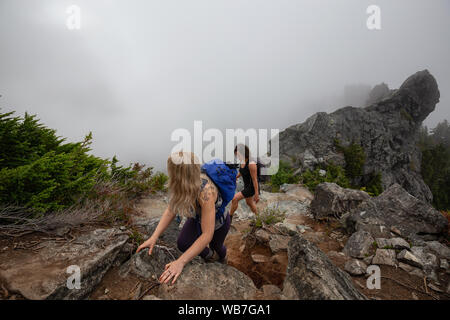 Abenteuerliche Mädchen ist Wandern auf einem steilen Weg nach oben einen schönen Rocky Mountain bei einem bewölkten Sommermorgen. Auf Crown Mountain, North Vancouver, BC genommen Stockfoto