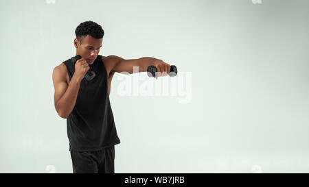 Perfekte Bizeps. Muskulösen jungen afrikanischen Mann Training mit Kurzhanteln, während gegen grauen Hintergrund stehen. Studio gedreht. Sport Konzept Stockfoto