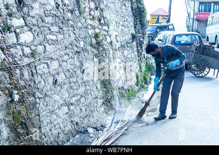 Shimla, Himachal Pradesh, Indien - 20. Juli 2019: städtische Arbeiter auf die Straße und Entwässerung Schleife mit Besen und sammelt Müll, Abwasser worke Stockfoto