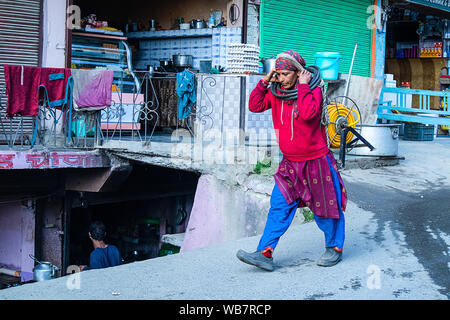 Shimla, Himachal Pradesh, Indien - 20. Juli 2019: Indische Frauen gehen auf die Straße. schweres Heben elektrische Kabel rollen auf den Kopf. Stockfoto