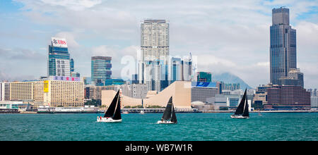 Boote segeln im Victoria Hafen mit Gebäuden auf der Kowloon Halbinsel im Hintergrund. Hongkong, China. Stockfoto