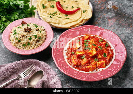 Paneer Makhani, Jeera Reis und paratha in rosa Platte auf dunklem Hintergrund. Paneer Makhani ist eine indische Küche curry mit paneer Käse, Tomaten und sp Stockfoto