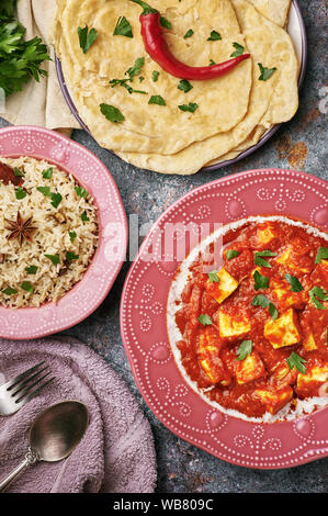 Paneer Makhani, Jeera Reis und paratha in rosa Platte auf dunklem Hintergrund. Paneer Makhani ist eine indische Küche curry mit paneer Käse, Tomaten und sp Stockfoto