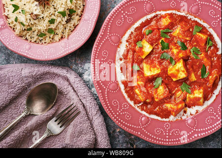 Paneer Makhani, Jeera Reis und paratha in rosa Platte auf dunklem Hintergrund. Paneer Makhani ist eine indische Küche curry mit paneer Käse, Tomaten und sp Stockfoto