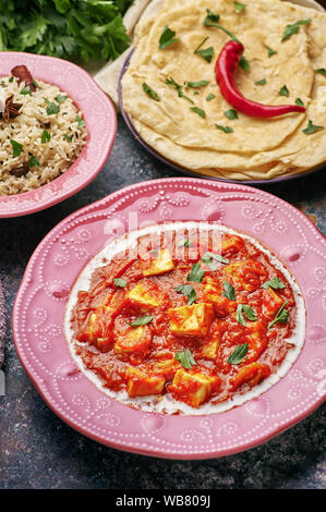 Paneer Makhani, Jeera Reis und paratha in rosa Platte auf dunklem Hintergrund. Paneer Makhani ist eine indische Küche curry mit paneer Käse, Tomaten und sp Stockfoto