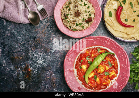 Paneer Makhani, Jeera Reis und paratha in rosa Platte auf dunklem Hintergrund. Paneer Makhani ist eine indische Küche curry mit paneer Käse, Tomaten und sp Stockfoto