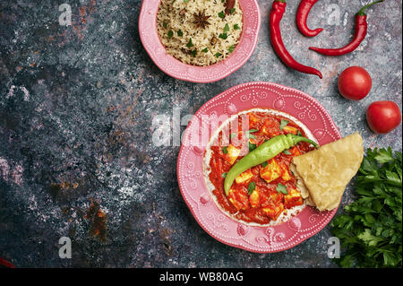 Paneer Makhani, Jeera Reis und paratha in rosa Platte auf dunklem Hintergrund. Paneer Makhani ist eine indische Küche curry mit paneer Käse, Tomaten und sp Stockfoto