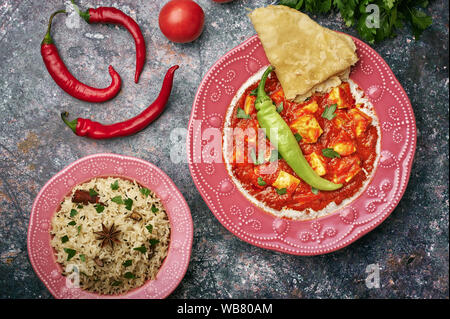 Paneer Makhani, Jeera Reis und paratha in rosa Platte auf dunklem Hintergrund. Paneer Makhani ist eine indische Küche curry mit paneer Käse, Tomaten und sp Stockfoto