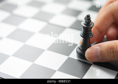 Geschäftsmann mit einem König Schach ist auf einem Schachbrett platziert. Verwendung als Hintergrund Business Konzept und Strategie konzept mit Platz für Ihren Text kopieren oder Stockfoto