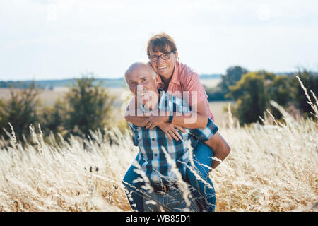 Älterer Mann, der seine Frau Huckepack auf bis zurück Stockfoto