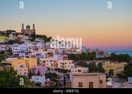 Panoramablick auf die Stadt Ermoupoli auf Syros Island in den Kykladen, Griechenland. Blick auf die farbenfrohen Häuser, den Hafen und die orthodoxe Kirche Anastaseos bei Sonnenuntergang Stockfoto