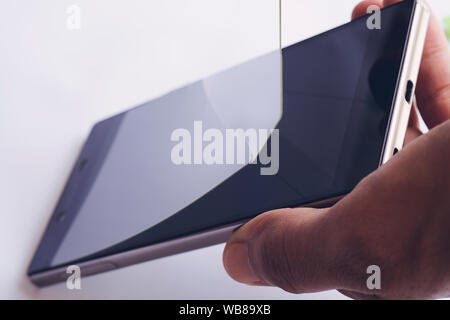 Hand entfernen beschädigt und Buntglasfenstern schützende Bildschirm des Smartphones film Stockfoto