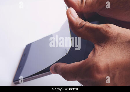 Hand entfernen beschädigt und Buntglasfenstern schützende Bildschirm des Smartphones film Stockfoto