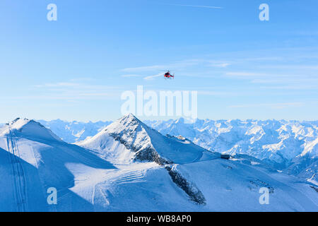 Fliegenden Roten Helikopter über Skigebiet Hintertuxer Gletscher im Zillertal in Tirol in Österreich im Winter in den Alpen. Häcksler und alpinen Berge mit Schnee. Ai Stockfoto