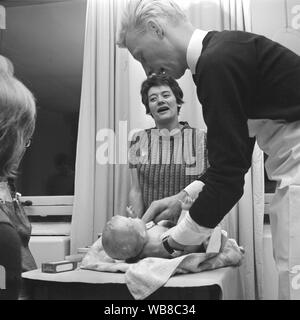Lernen zu haben ein Baby in den 1960er Jahren. Eine Klasse, wie Sie kümmern sich um ein Baby. Eine Klasse, die Männer und Frauen, wenn Sie über die Eltern werden zum ersten Mal gehen. März 1963. Schweden Stockfoto