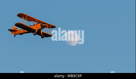 Eine antike American bi-plane flying Overhead in der Abenddämmerung bei Vollmond und ein blauer Himmel. Stockfoto