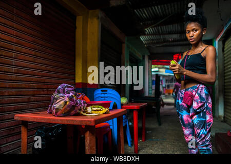 Ein Afro girl schält sie kochen Banane in einem Street Restaurant im Markt der Bazurto in Cartagena, Kolumbien. Stockfoto