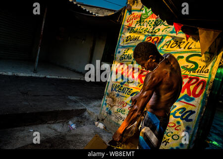 Eine afrokolumbianischen Obdachlosen Tränen aus Kartons vor der Wand, mit Propaganda bedeckt, auf dem Markt der Bazurto in Cartagena, Kolumbien. Stockfoto