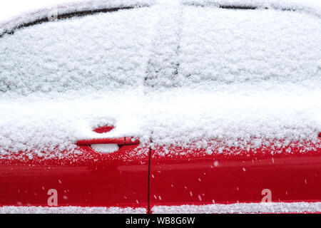 Rotes Auto im Schnee. Die Fenster des Autos sind mit Schnee bedeckt Stockfoto