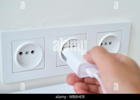 Männliche Hand weißen Stecker in Buchse Stockfoto