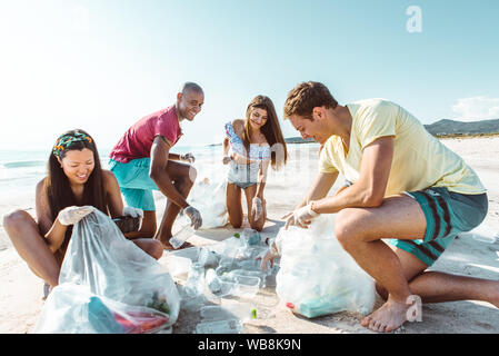 Gruppe von Aktivisten Freunde sammeln Plastikmüll am Strand. Die Leute am Strand, Reinigung, mit Taschen. Konzept über den Umweltschutz ein Stockfoto