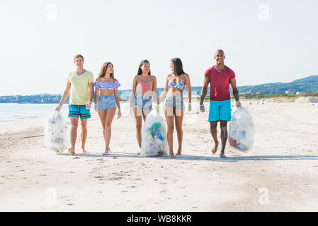 Gruppe von Aktivisten Freunde sammeln Plastikmüll am Strand. Die Leute am Strand, Reinigung, mit Taschen. Konzept über den Umweltschutz ein Stockfoto