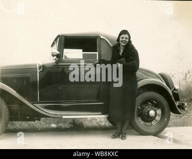 Gelbliches Foto von 1933 einer jungen Frau mit einem Ford Model A Sport Coupé um 1928-1932. Stockfoto