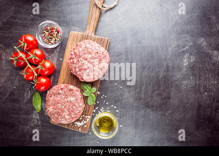 Frische rohe Prime Black Angus Beef Burger Pastetchen auf schwarzem Hintergrund. Ansicht von oben. Stockfoto